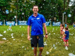 A camp staff member smiling while soap bubbles are floating in the air.
