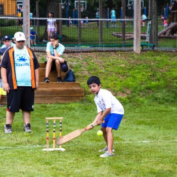 A camper playing cricket and getting ready to hit the ball.