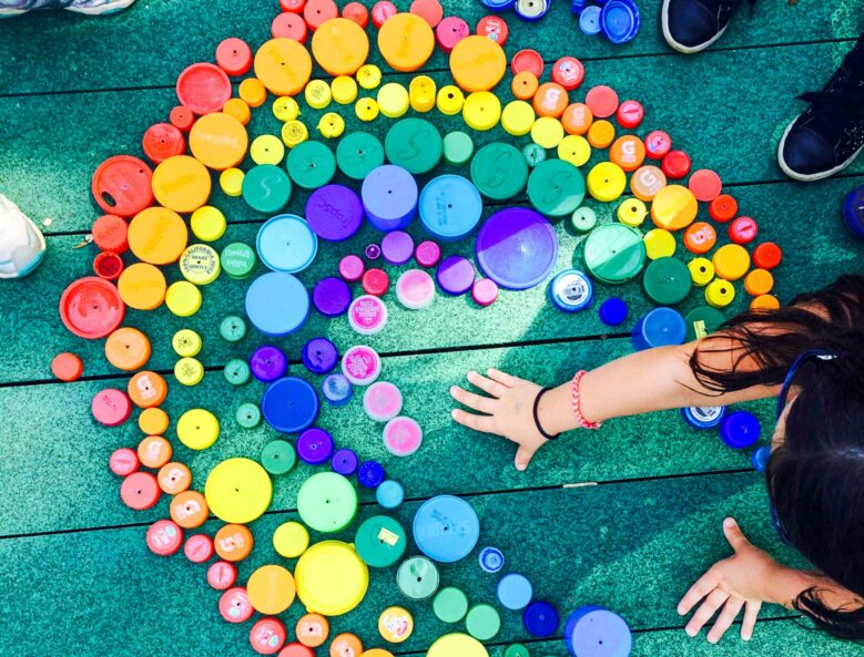 Campers creating a rainbow mosaic with bottle caps.